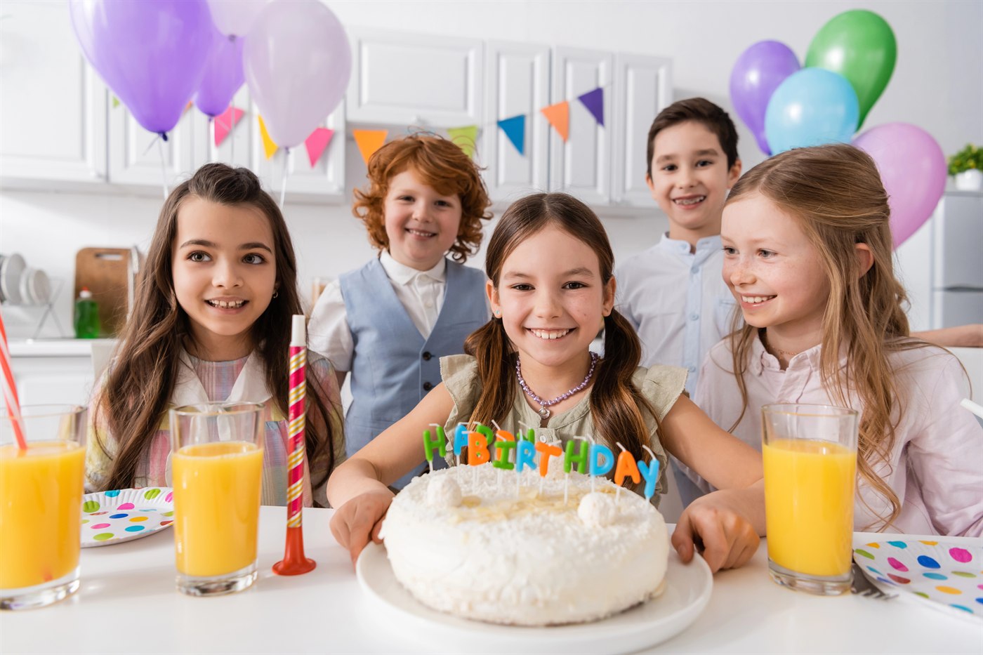 Children celebrating a birthday with cake and balloons